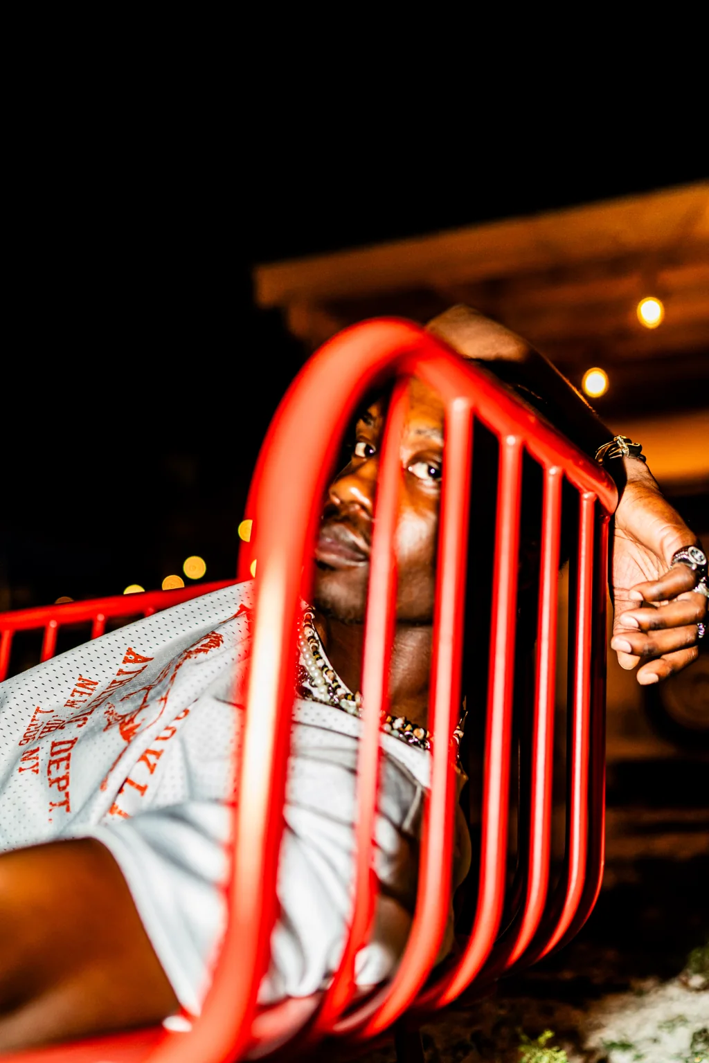A man framed through red playground bars at night
